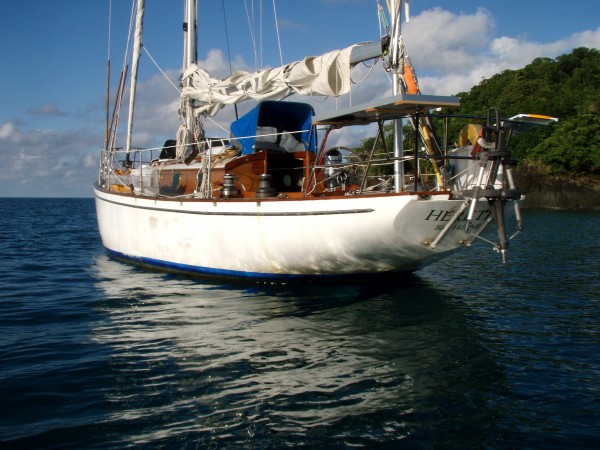 green sailing - Heretic with her wind vane and solar panels visible on the stern